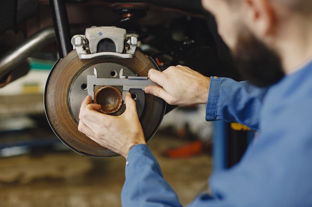 Mechanic with a tool. Wheel in hands of a mechanic. Blue work clothes.