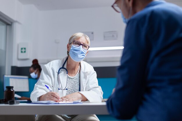 Medic signing appointment papers at checkup visit with man during pandemic