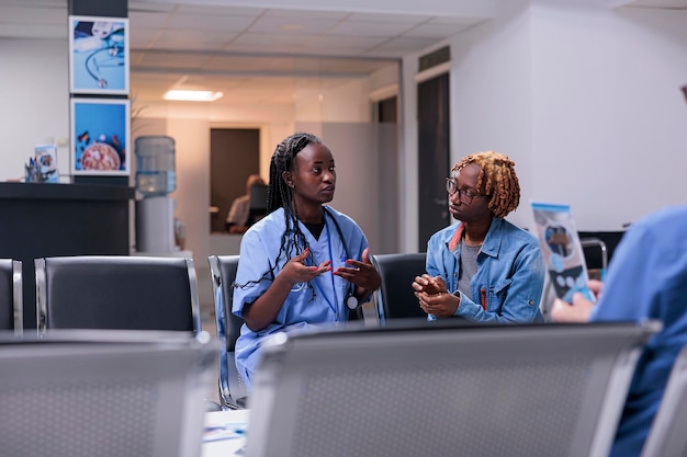 Medical assistant consulting woman at clinic, talking about disease and healthcare at checkup visit examination appointment. Nurse and patient doing consultation in waiting room.