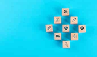 Free photo medical check up concept with wooden blocks with icons on blue table flat lay.