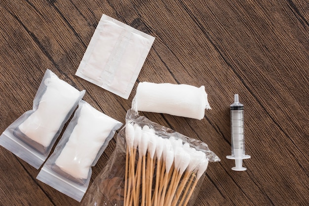 Free Photo medical cotton gauze bandage; syringe and pack of cotton swab on wooden table