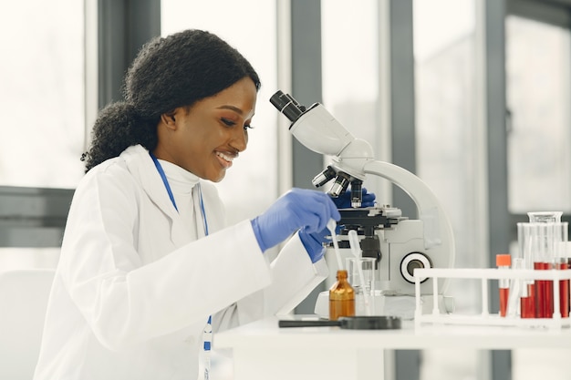 Medical doctor girl working with a microscope. Young female scientist doing vaccine research.