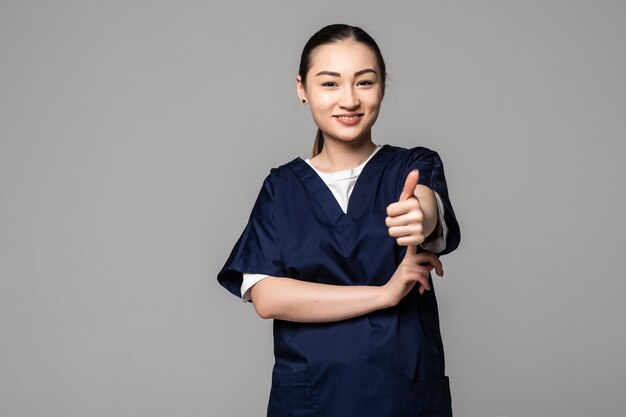 Medical doctor showing thumbs up sign on gray wall