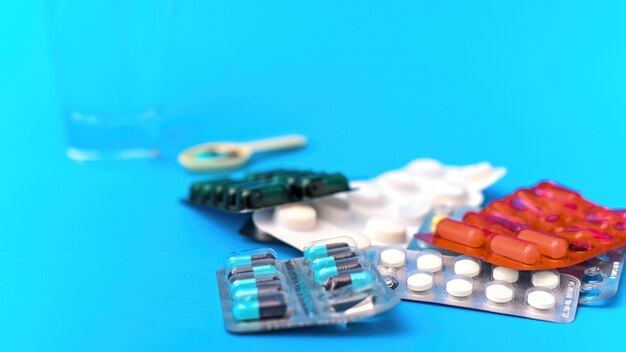 Medical supplies and items composition on blue background. Stack of pill packs