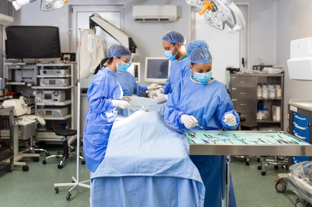 Free photo medical team performing operation group of surgeon at work in operating theatre toned in blue doctor operation in operation room at hospital concept for insurance advertising