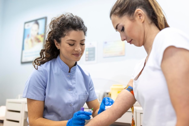 Medical technologist doing a blood draw services for patient lab assistant with sterile rubber gloves taking blood sample from patient