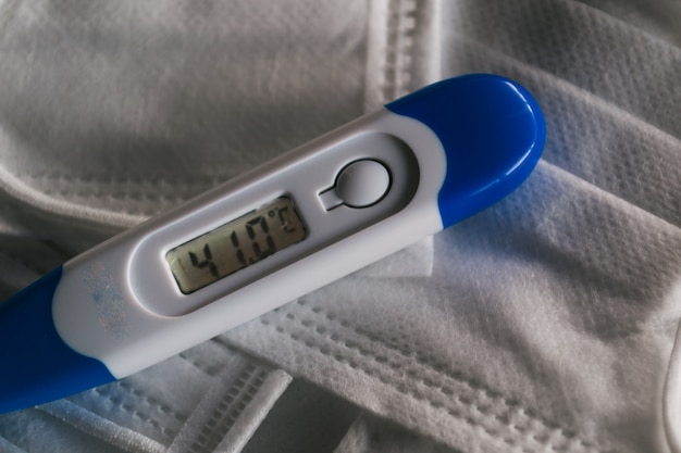 Free photo medical thermometer indicating high temperature on the face masks-coronavirus