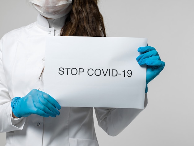 Free photo medical worker holding stop covid-19 leaflet