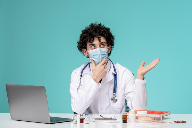 Medical young handsome doctor working on computer remotely in lab coat looking up