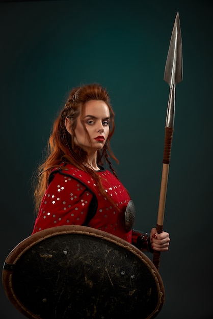 Free photo medieval female warrior posing with spear, shield.