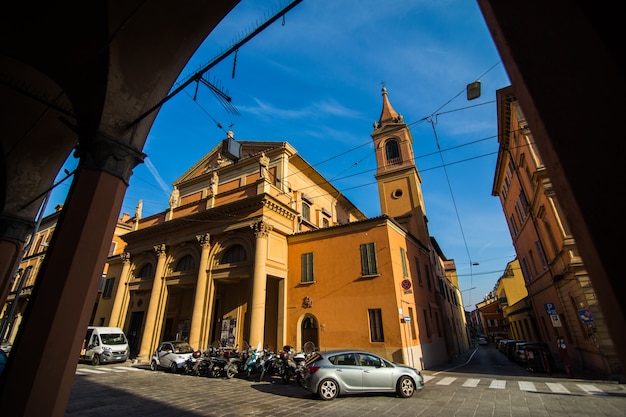 Medieval street portico with bright colored houses in the Old Town in the sunny day, Bologna, Emilia-Romagna, Italy