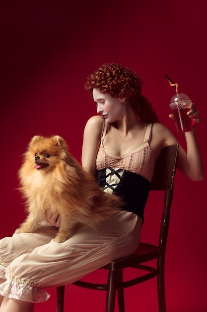 Free Photo medieval young woman drinking juice and holding little dog