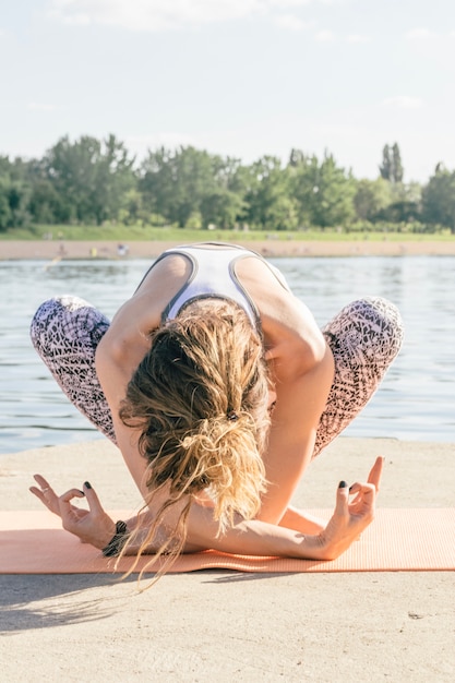 Free photo meditating young woman sitting at river