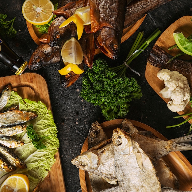 Mediterranean food, smoked Herring fish served with green onion, lemon, cherry tomatoes, spices, bread and Tahini sauce on dark.Top view with close-up