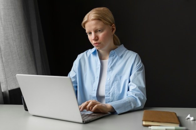 Medium shot albino woman working on laptop