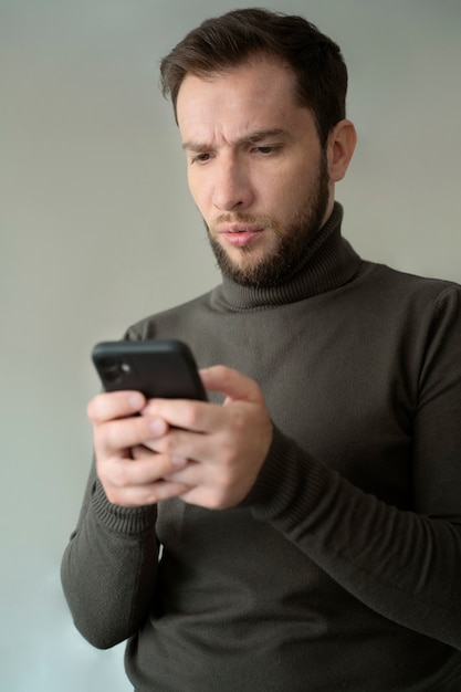 Medium shot anxious man holding smartphone