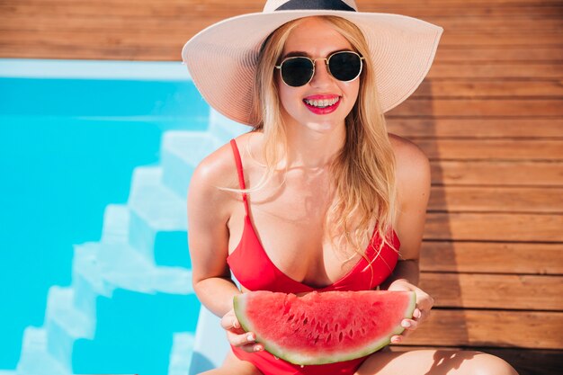 Medium shot blonde woman holding a watermelon