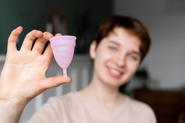 Medium shot blurry woman holding menstrual cup