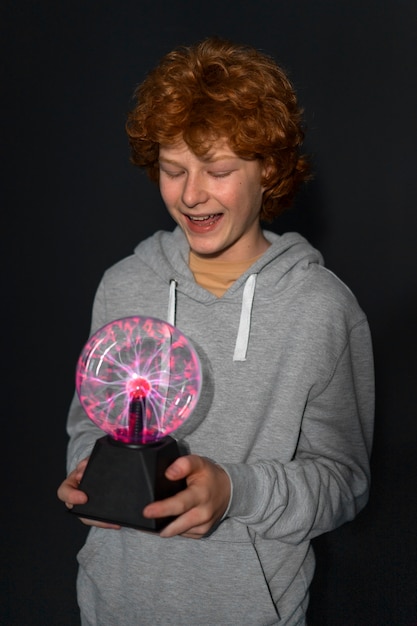 Free photo medium shot boy interacting with a plasma ball