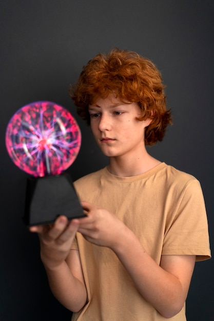 Free photo medium shot boy interacting with a plasma ball