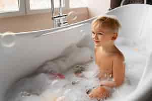 Free photo medium shot boy playing in bathtub