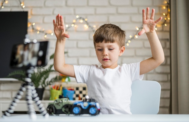 Medium shot boy recording with cars