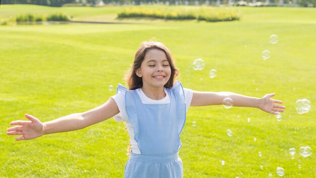 Medium shot cheerful girl playing with soap bubbles