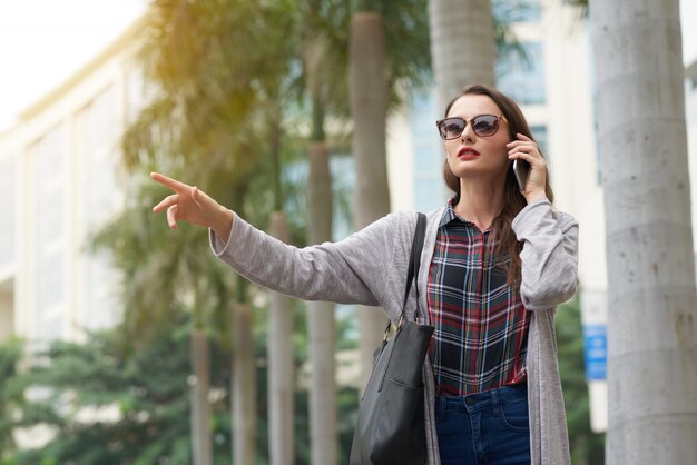 Medium shot of city dweller taking a car with a gesture