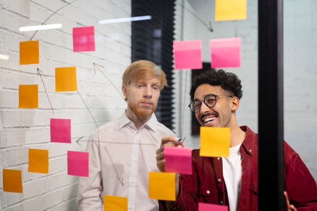 Free photo medium shot colleagues looking at post its