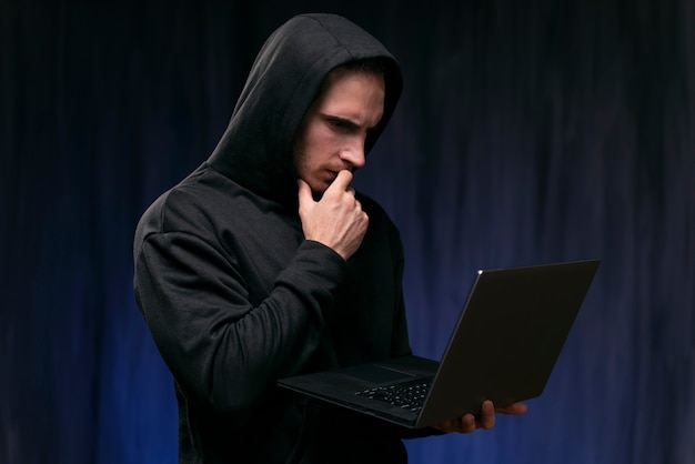 Medium shot concerned hacker holding laptop