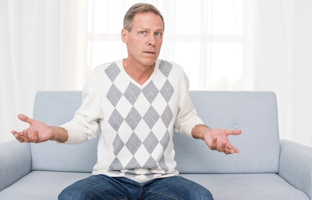 Medium shot confused man sitting on the couch