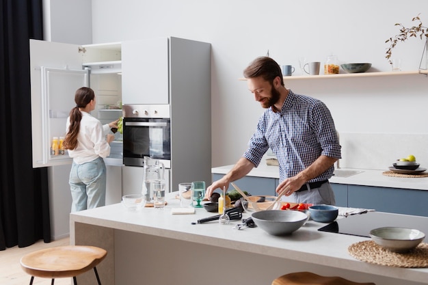 Medium shot couple cooking in kitchen