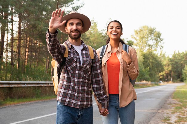 Medium shot couple greeting someone while traveling