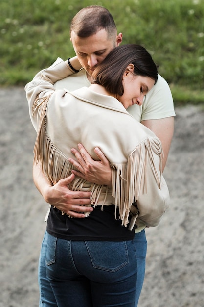 Free Photo medium shot couple hugging outdoors