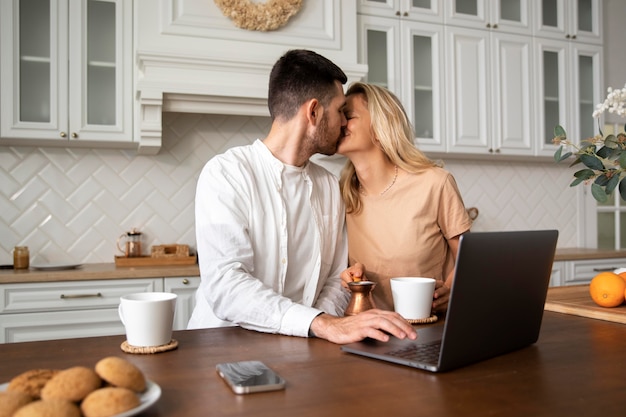 Medium shot couple kissing in kitchen