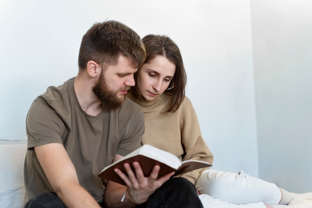 Medium shot couple reading bible together