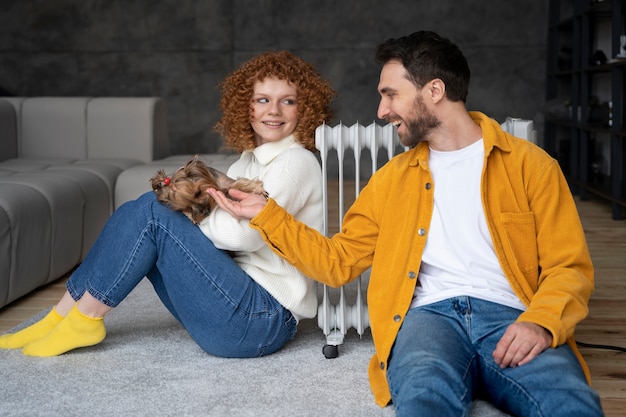 Medium shot couple sitting near heater