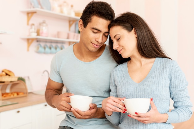 Free photo medium shot couple with mugs in the kitchen