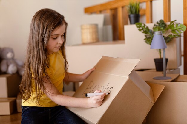 Medium shot cute girl writing on box