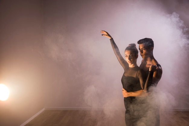 Free photo medium shot dancers couple in smoke