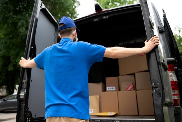 Free photo medium shot delivery man looking at boxes