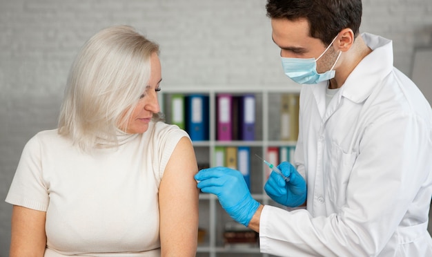 Medium shot doctor administering vaccine