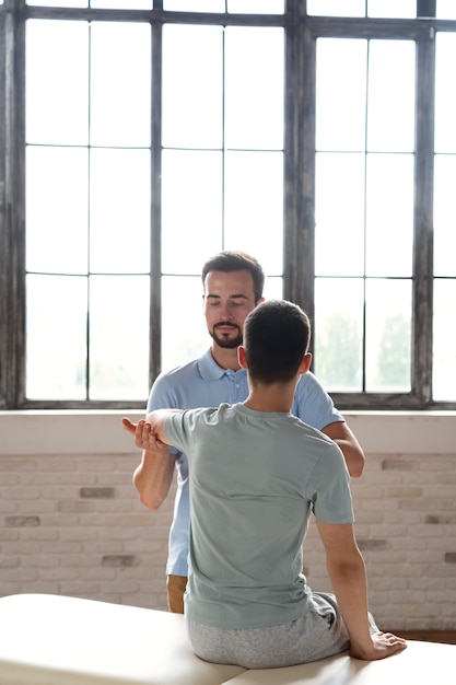 Free photo medium shot doctor helping patient in physiotherapy