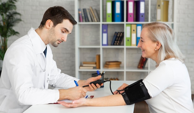 Free photo medium shot doctor taking blood pressure