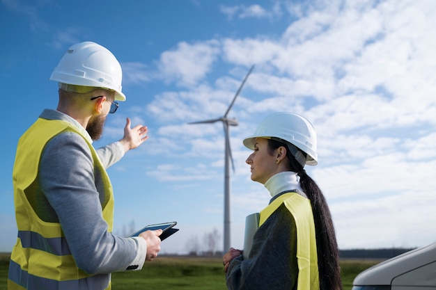 Free Photo medium shot engineers chatting about wind power plant