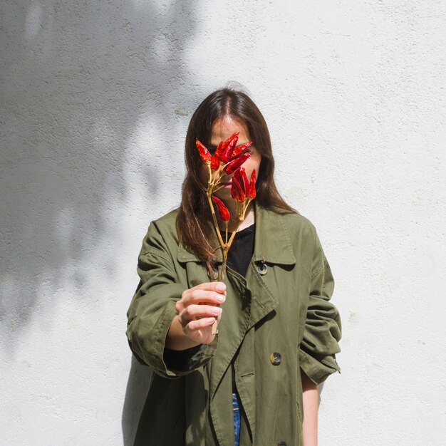 Medium shot fashion woman covering her face with bunch of peppers