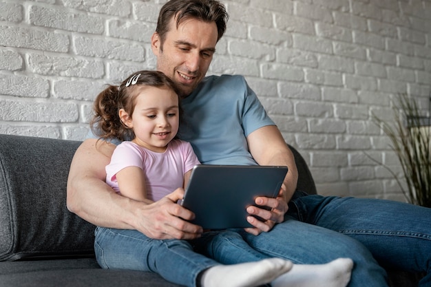 Free photo medium shot father and girl with tablet