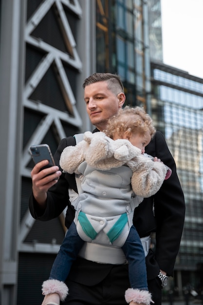 Free photo medium shot father holding baby in carrier