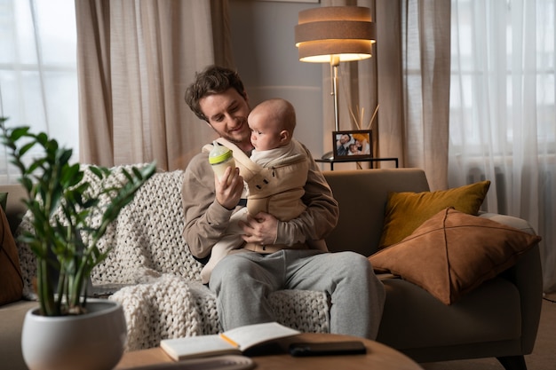 Medium shot father holding cute baby in carrier