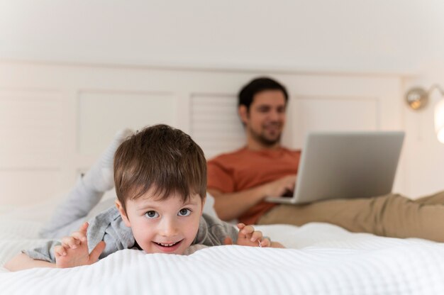 Medium shot father and kid in bed